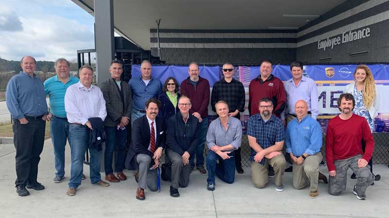 A group of symposium participants poses during the UPS SMART Hub tour, which gave them an up-close look at the second-largest ground package processing facility in the U.S.